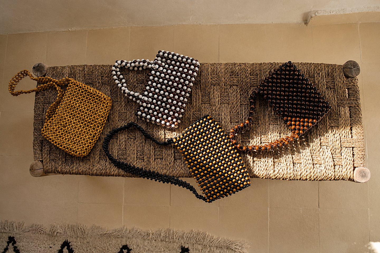 An overhead still life of handcrafted beaded bags on a woven bench.