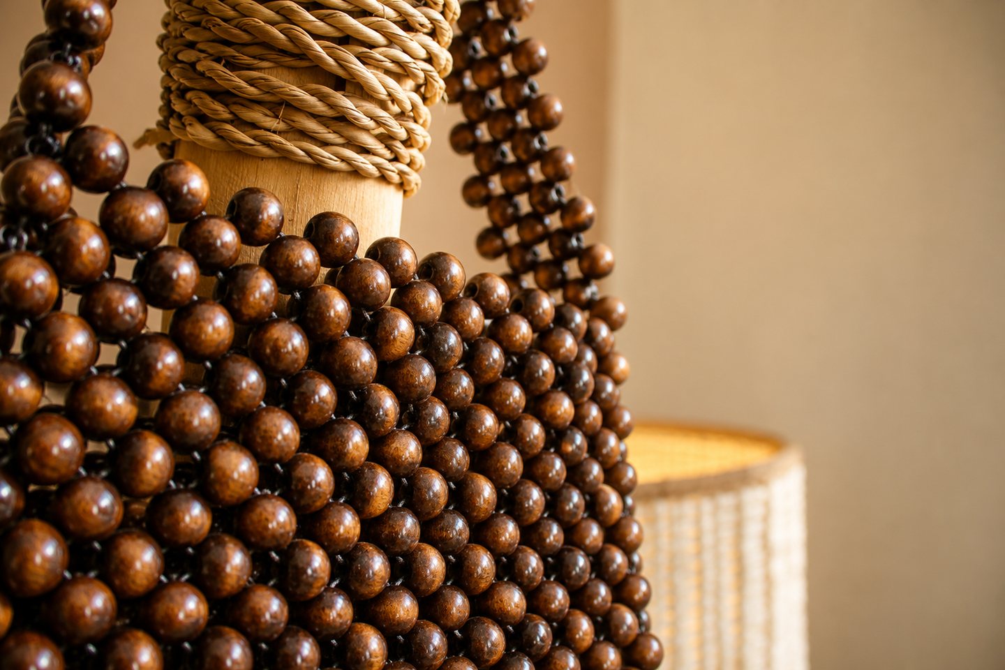 Close view of wooden beads, braided fibre and warm natural textures.