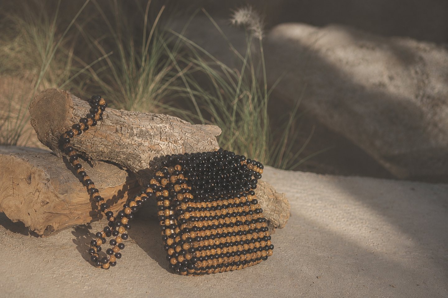 Black and ochre beadwork resting against rough timber and stone.