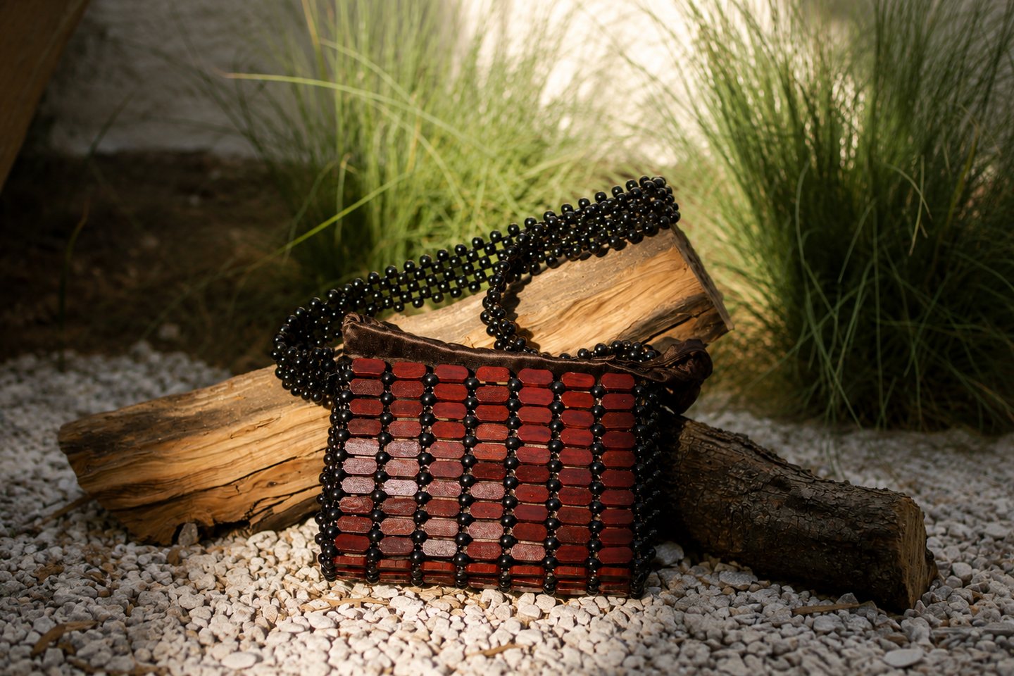 A finished red and black beaded bag staged with weathered wood.