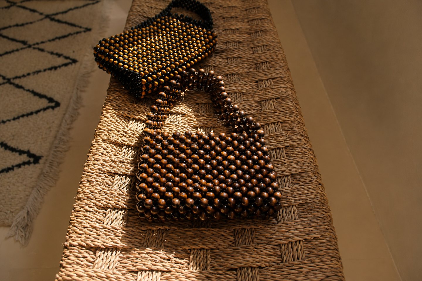 A group of beaded bags arranged across woven surfaces in directional light.