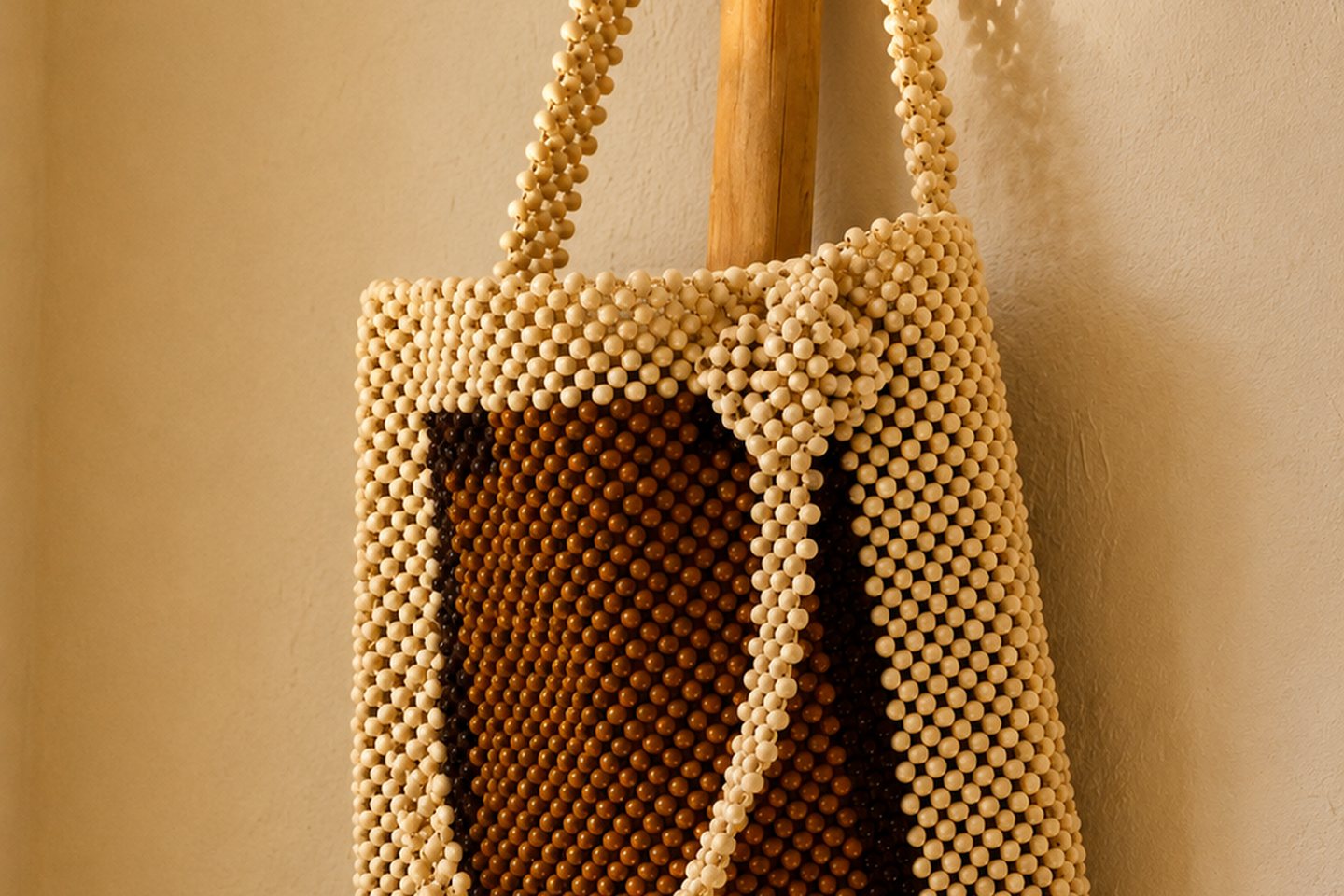 A structured cream and brown beaded tote shown at full scale.